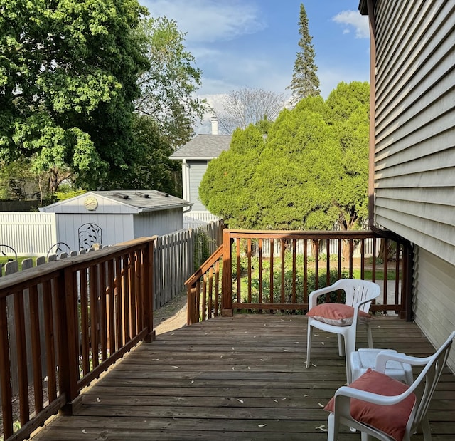 wooden terrace with a fenced backyard, an outdoor structure, and a storage shed