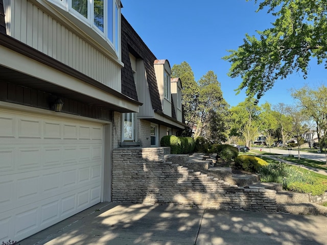 view of home's exterior with mansard roof and an attached garage