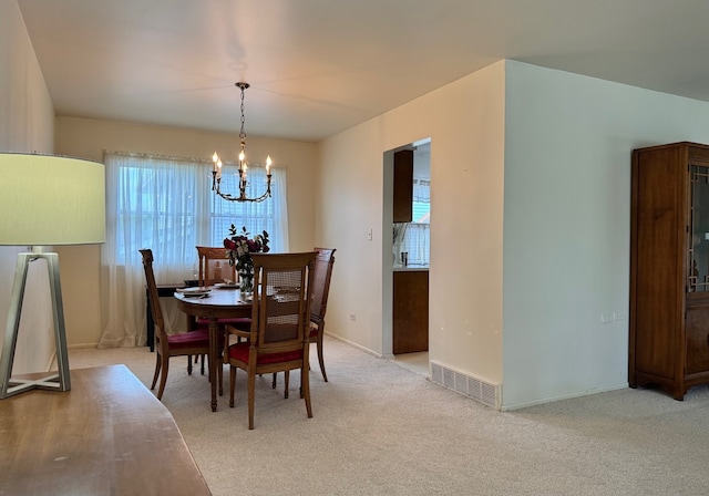 dining room with a chandelier, light colored carpet, and baseboards