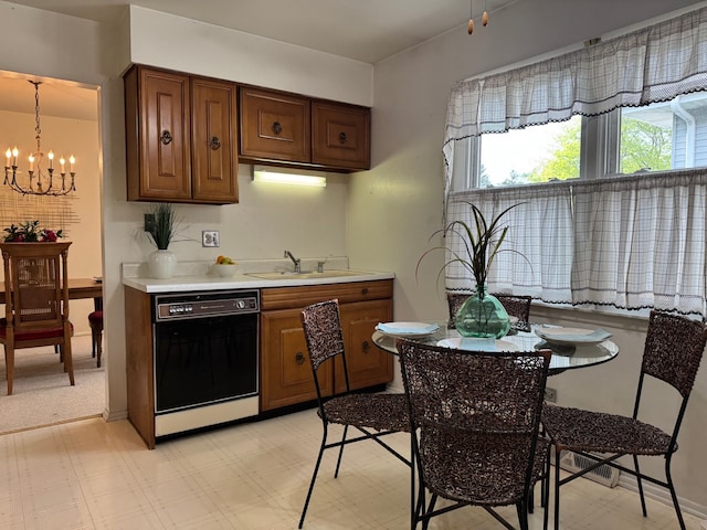 kitchen with black dishwasher, a sink, a chandelier, light countertops, and light floors