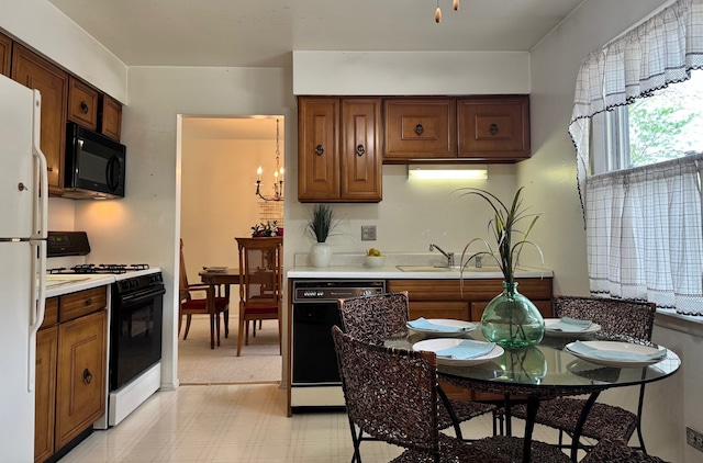 kitchen with black appliances, a chandelier, brown cabinets, light countertops, and a sink