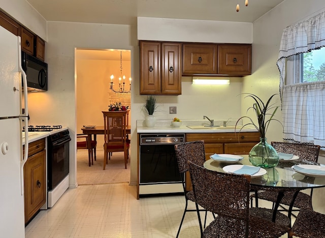 kitchen with black appliances, a sink, a chandelier, light countertops, and light flooring