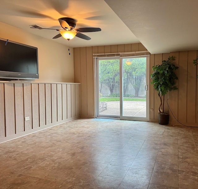 spare room featuring wooden walls and a ceiling fan