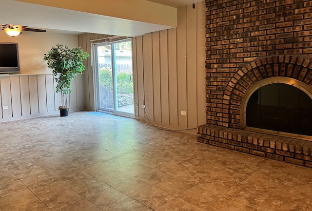 unfurnished living room featuring wood walls and ceiling fan