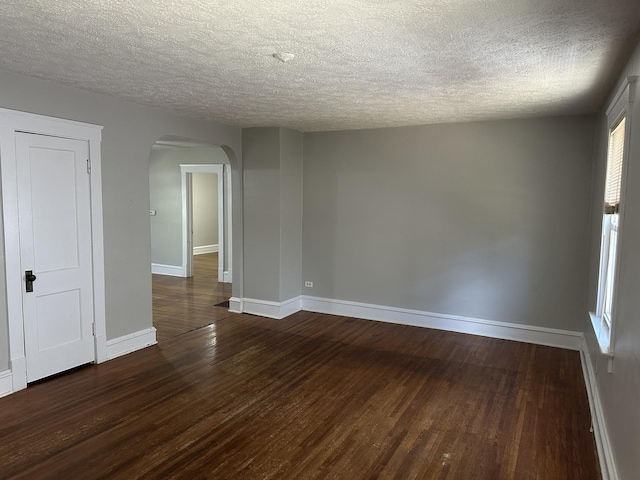 1406 W Locust St, Bloomington, IL 61701 - unfurnished room with arched walkways, wood finished floors, a textured ceiling, and baseboards