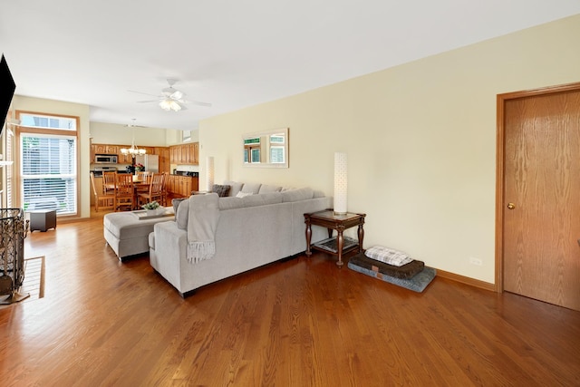living area featuring a ceiling fan, a chandelier, wood finished floors, and baseboards