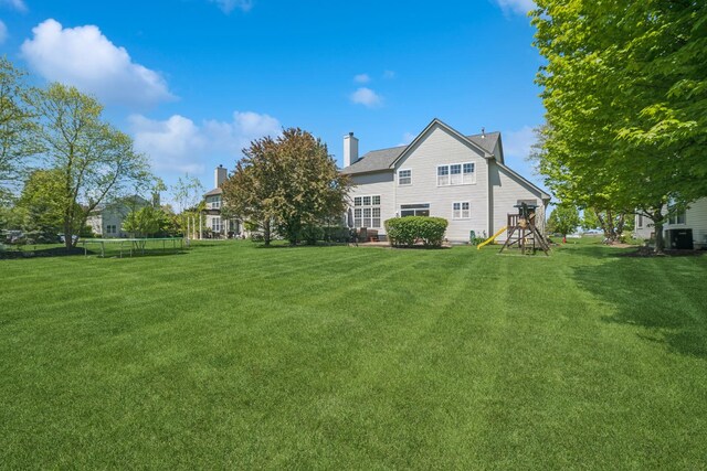 718 Northgate Dr, Sycamore, IL 60178 - rear view of house with a playground, a yard, a trampoline, and central AC