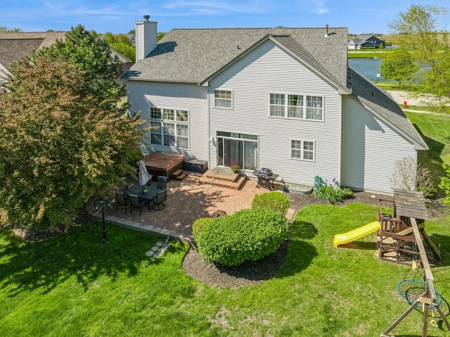 718 Northgate Dr, Sycamore, IL 60178 - rear view of property featuring a patio, a yard, a chimney, a playground, and roof with shingles