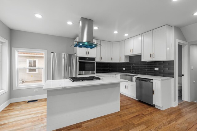 12725 S Wallace St, Chicago, IL 60628 - kitchen with stainless steel appliances, a sink, island exhaust hood, tasteful backsplash, and white cabinetry