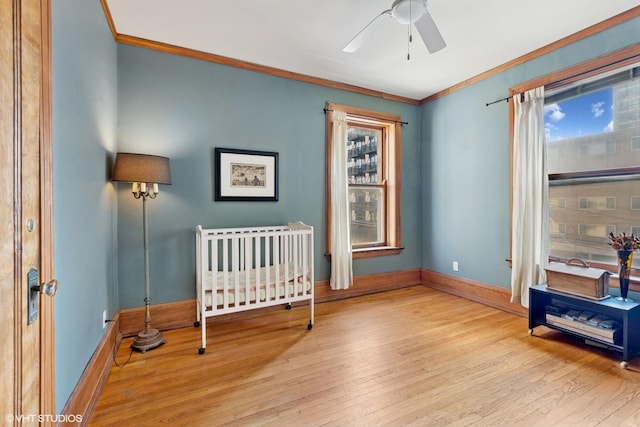 bedroom with wood finished floors, ornamental molding, multiple windows, and baseboards