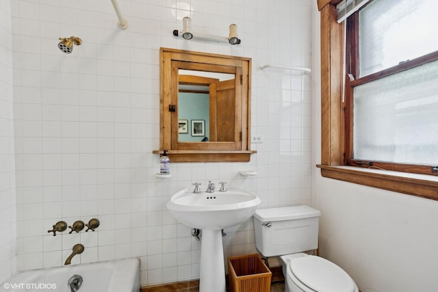 full bathroom with tile walls, a tub, and toilet