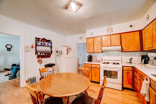 218 W Fleming St, Watseka, IL 60970 - kitchen featuring white appliances, under cabinet range hood, light wood finished floors, light countertops, and tasteful backsplash