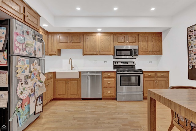 724 12th St Unit 303, Wilmette, IL 60091 - kitchen with appliances with stainless steel finishes, a sink, light wood-style flooring, light countertops, and brown cabinetry