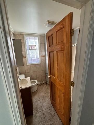 8370 S Baker Ave, Chicago, IL 60617 - bathroom featuring tile patterned flooring, vanity, toilet, and tile walls