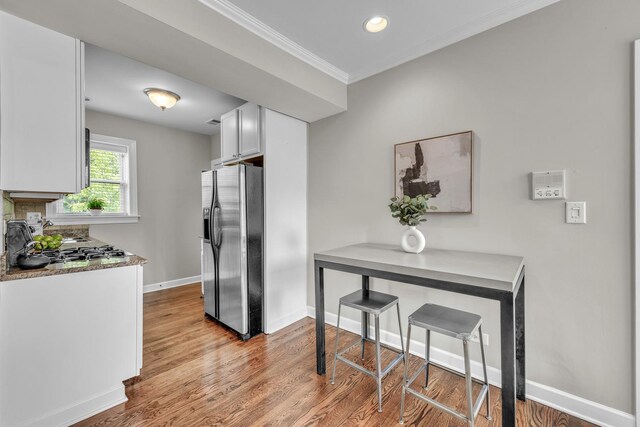 1438 W Roscoe St Unit 3, Chicago, IL 60657 - kitchen featuring stainless steel fridge, wood finished floors, white cabinetry, crown molding, and recessed lighting