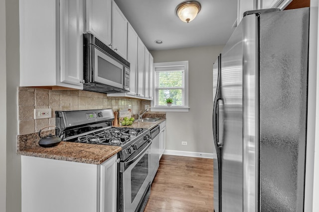 1438 W Roscoe St Unit 3, Chicago, IL 60657 - kitchen featuring stainless steel appliances, wood finished floors, white cabinetry, backsplash, and stone countertops