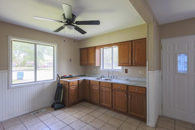 885 163rd St, Calumet City, IL 60409 - kitchen with a sink, light countertops, brown cabinets, light tile patterned floors, and wainscoting