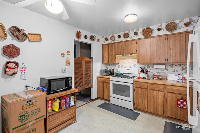859 N Gladstone Ave, Aurora, IL 60506 - kitchen with white range with gas cooktop, black microwave, under cabinet range hood, light countertops, and brown cabinetry