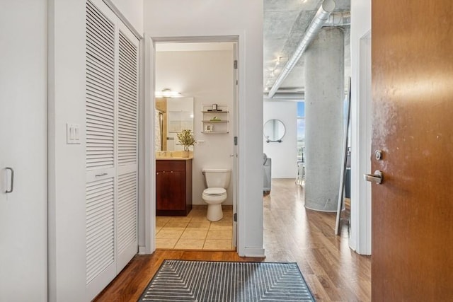 bathroom with a closet, wood finished floors, vanity, and toilet