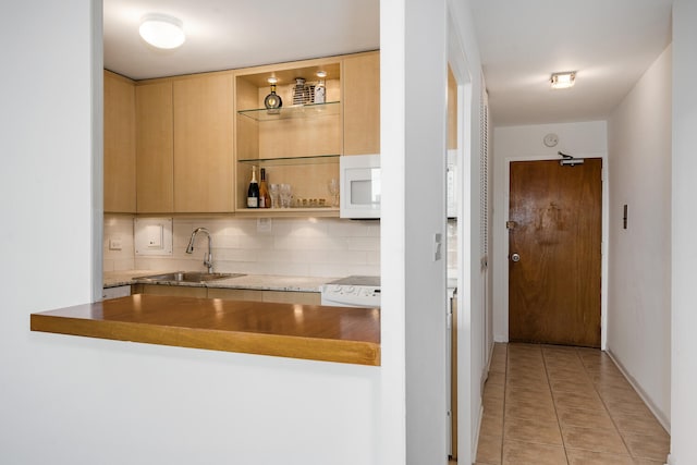 555 W Cornelia Ave Unit 1405, Chicago, IL 60657 - kitchen featuring a sink, white microwave, backsplash, light tile patterned floors, and light brown cabinetry