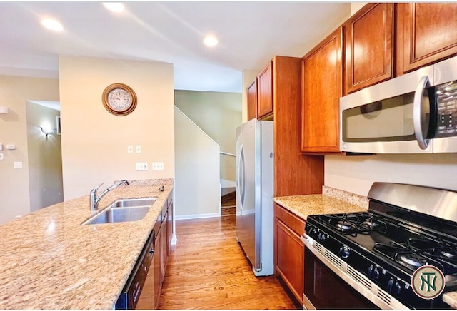 4532 S Woodlawn Ave, Chicago, IL 60653 - kitchen with appliances with stainless steel finishes, a sink, light wood-type flooring, brown cabinets, and light stone counters