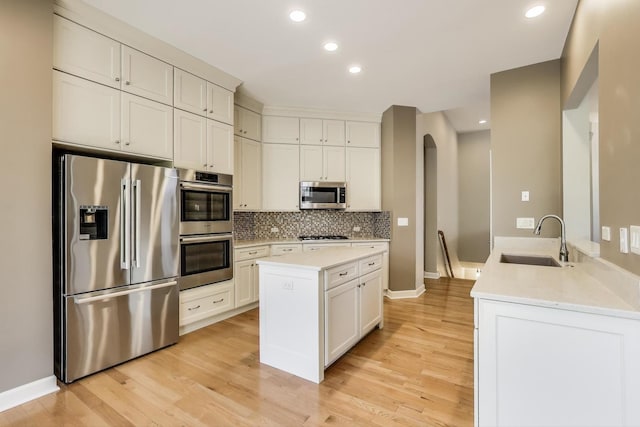 2334 Glen Eagles Ln, Riverwoods, IL 60015 - kitchen featuring appliances with stainless steel finishes, a sink, light wood-style flooring, arched walkways, and recessed lighting