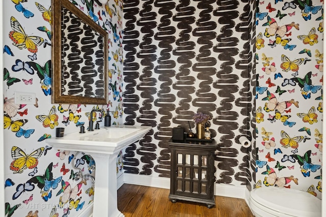 bathroom with wood finished floors, toilet, and baseboards