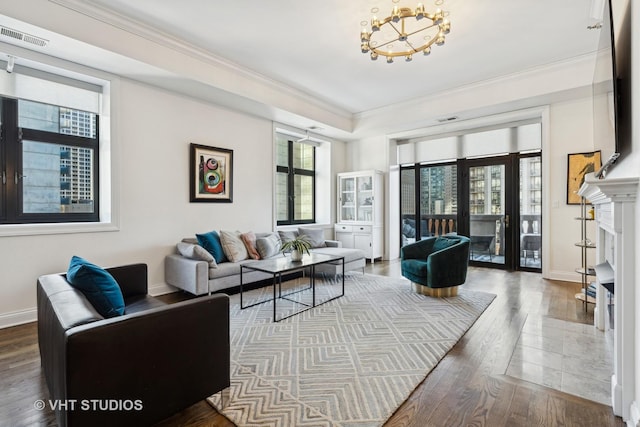 living room featuring a chandelier, plenty of natural light, ornamental molding, wood finished floors, and baseboards