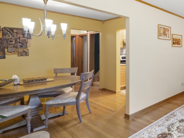 4129 N Mcvicker Ave, Chicago, IL 60634 - dining space featuring a chandelier, light wood-type flooring, baseboards, and ornamental molding