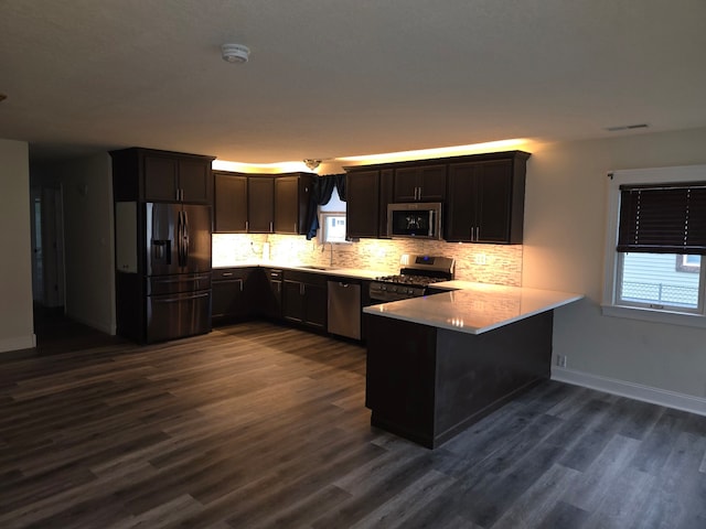 1614 Poplar St, Ottawa, IL 61350 - kitchen featuring appliances with stainless steel finishes, a peninsula, a sink, backsplash, and dark wood finished floors
