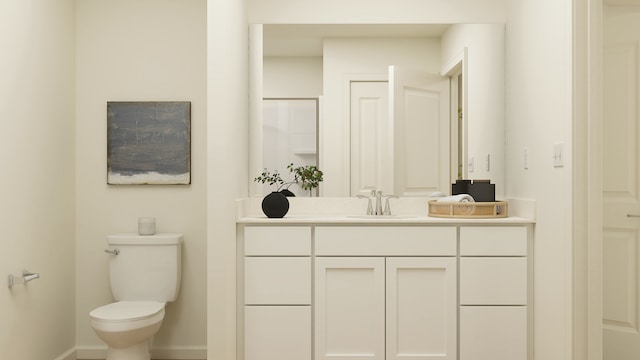 bathroom featuring toilet, baseboards, and vanity