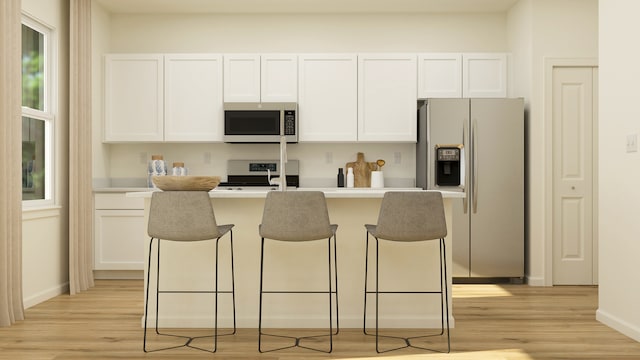 kitchen featuring appliances with stainless steel finishes, white cabinets, a breakfast bar, and a kitchen island with sink