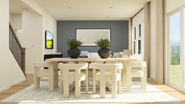 dining room featuring light wood finished floors, baseboards, and stairs