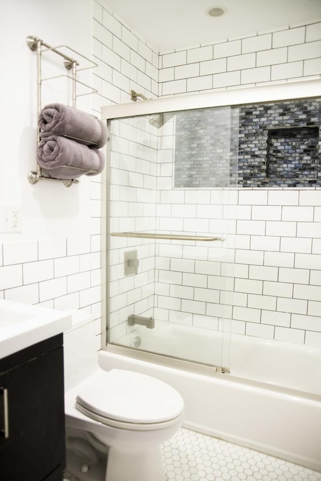 1703 Beverly Pl, Highland Park, IL 60035 - bathroom with bath / shower combo with glass door, tile walls, toilet, vanity, and tile patterned floors