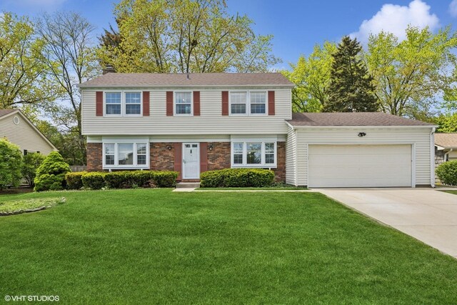 751 Essington Ln, Buffalo Grove, IL 60089 - colonial inspired home featuring a chimney, a garage, a front lawn, and driveway