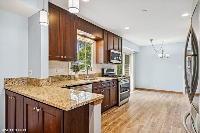751 Essington Ln, Buffalo Grove, IL 60089 - kitchen featuring a sink, stainless steel appliances, light wood-type flooring, decorative light fixtures, and light stone countertops
