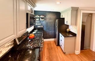 1010 N Patton Ave, Arlington Heights, IL 60004 - kitchen with stainless steel microwave, light wood-type flooring, dark countertops, and backsplash