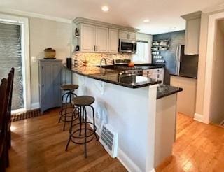 1010 N Patton Ave, Arlington Heights, IL 60004 - kitchen with stainless steel appliances, a peninsula, open shelves, a breakfast bar area, and light wood-style floors