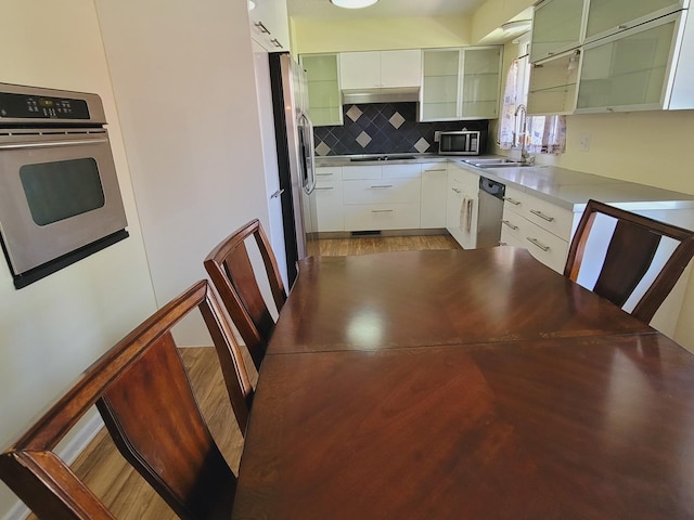 511 N Berwick Blvd, Waukegan, IL 60085 - kitchen featuring stainless steel appliances, backsplash, a sink, glass insert cabinets, and white cabinetry