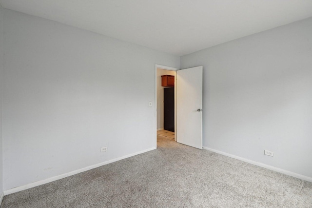 spare room with light colored carpet and baseboards