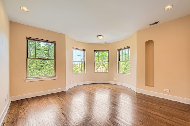 empty room with plenty of natural light, wood finished floors, baseboards, and recessed lighting