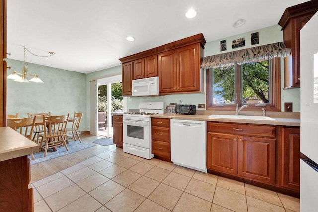 kitchen with white appliances, a sink, light countertops, brown cabinets, and light tile patterned flooring