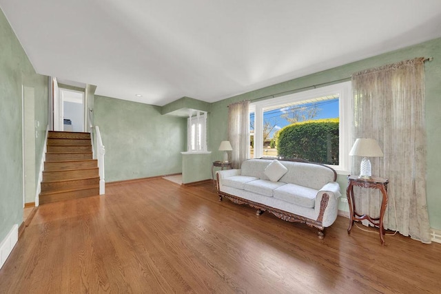 living room with wood finished floors, baseboards, and stairway