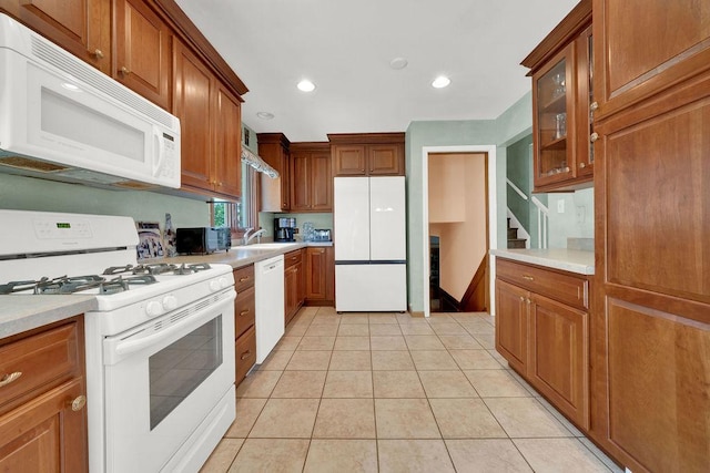 kitchen with white appliances, light countertops, light tile patterned floors, brown cabinets, and recessed lighting