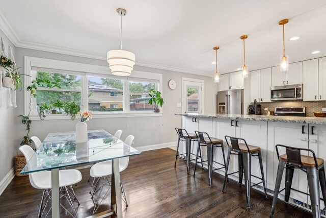 9017 Pottawattami Dr, Skokie, IL 60076 - kitchen featuring appliances with stainless steel finishes, baseboards, dark wood-type flooring, a breakfast bar area, and crown molding