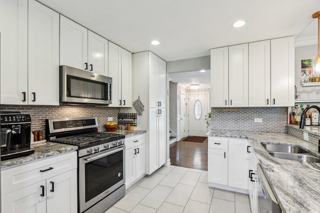 9017 Pottawattami Dr, Skokie, IL 60076 - kitchen with stainless steel appliances, a sink, light tile patterned floors, white cabinetry, and recessed lighting