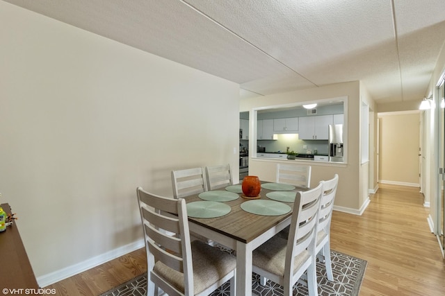 6980 W Touhy Ave Unit 201, Niles, IL 60714 - dining area featuring light wood finished floors, baseboards, and a textured ceiling