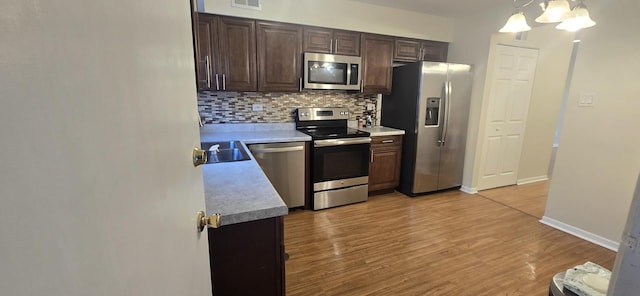 9356 Bay Colony Dr Unit 1S, Des Plaines, IL 60016 - kitchen featuring stainless steel appliances, decorative backsplash, dark brown cabinetry, light wood finished floors, and a chandelier