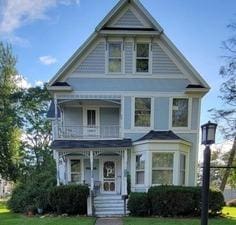 victorian home with a balcony, covered porch, and a front lawn