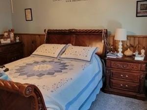 carpeted bedroom featuring a wainscoted wall and wooden walls